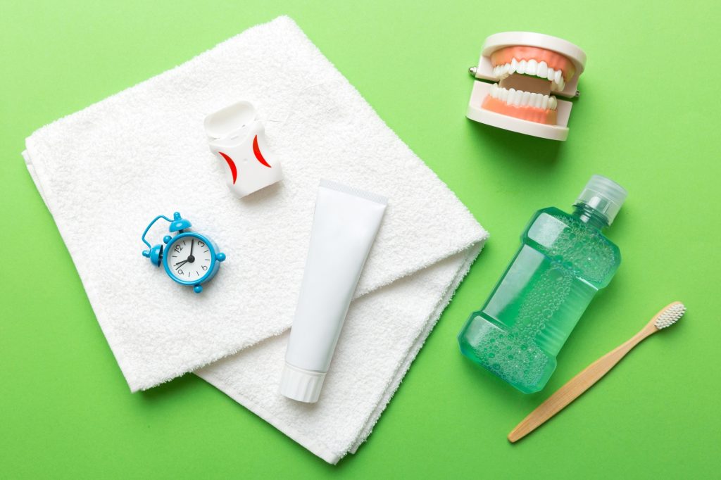 Essential oral hygiene products laid out on a green background