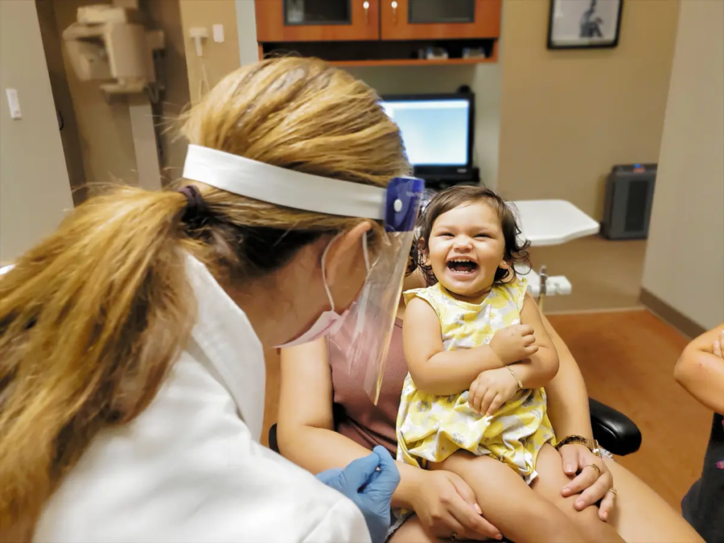 A smiling baby has fun during her first preventive dentistry checkup.